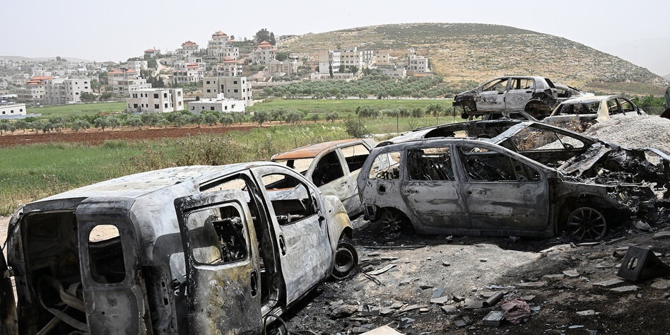 Ausgebrannte Autowracks vor einer Siedlung im Westjordanland