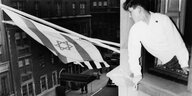 Ein Junge hisst die Flagge Israels von einem Fenster aus.